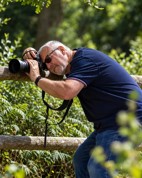 Steve Pullenger lining up a shot with his camera resting on a wooden fence