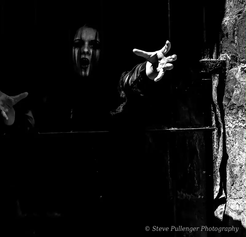 Pale face and reaching hand emerging from a dark doorway