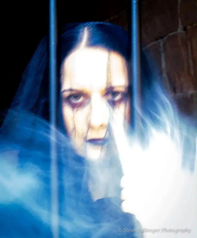 Veiled woman behind bars surrounded by swirling blue smoke